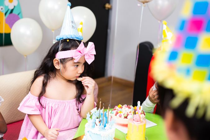 Cute girl at birthday party with cake and hats