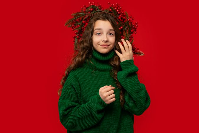 Teen girl wearing green sweater and Christmas berry wreath