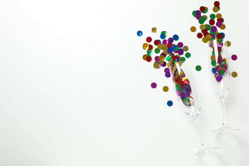 Champagne glasses with glitter on bright background, space for text
