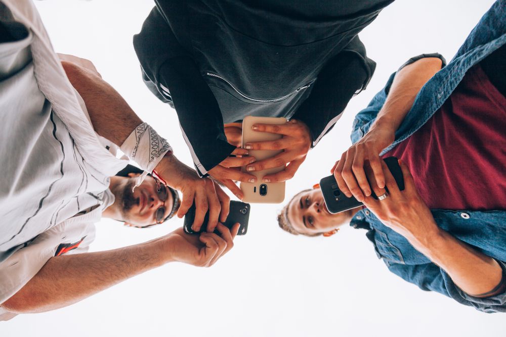 Stylish young people using smartphone outdoors