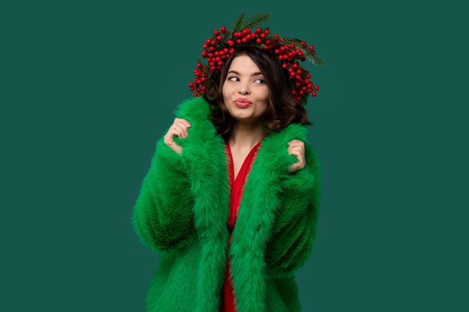 Woman in green coat and red berry wreath