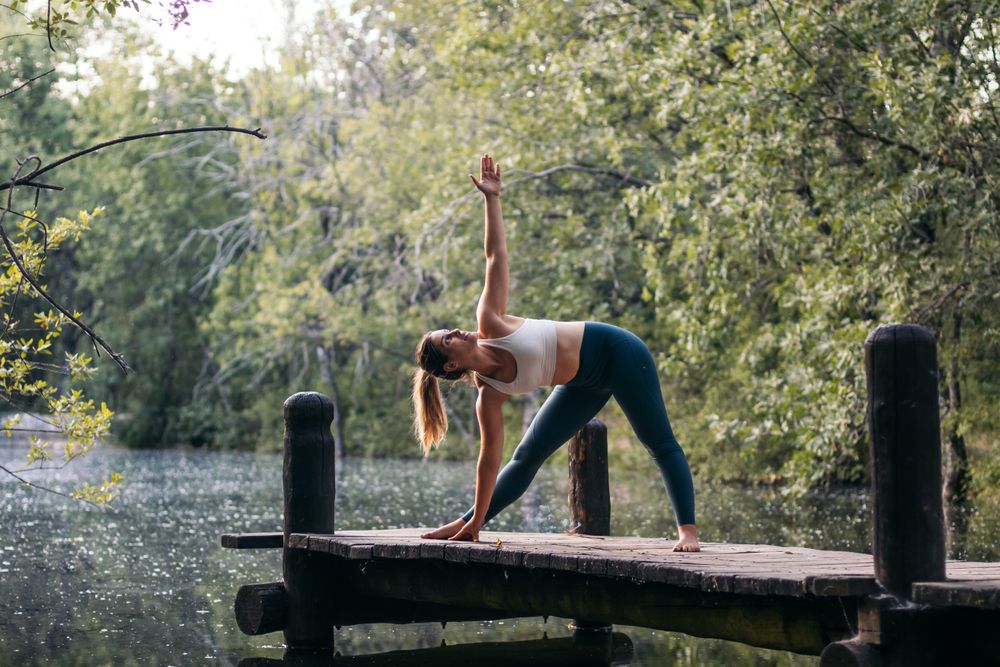 Woman in sportswear doing yoga outdoors near a lake
