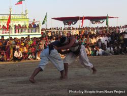 Two Indian men fighting in an outdoor arena while audience watching 48Eo7b