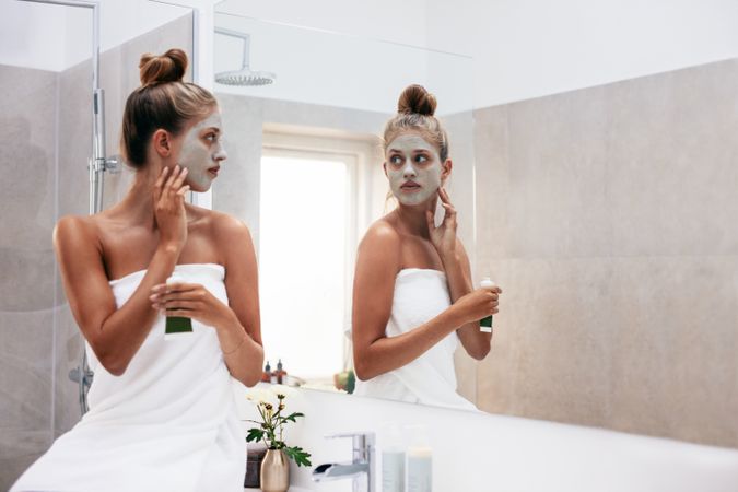 Beautiful female in front of mirror applying facial mask