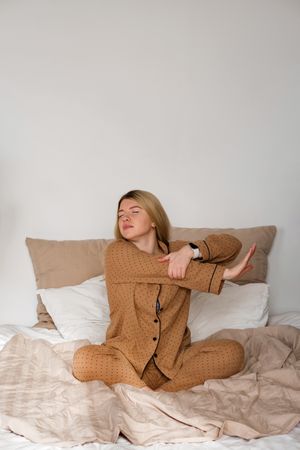 Woman stretching in pajamas with smartwatch