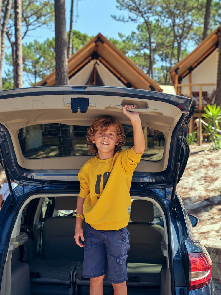 Boy standing in car trunk and looking at camera