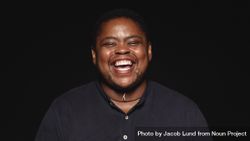 Transgender man laughing with eyes closed isolated on dark background bYOBX5