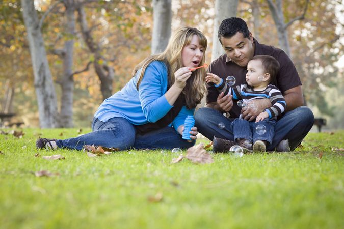 Fun Young Family Playing with Bubbles In The Park