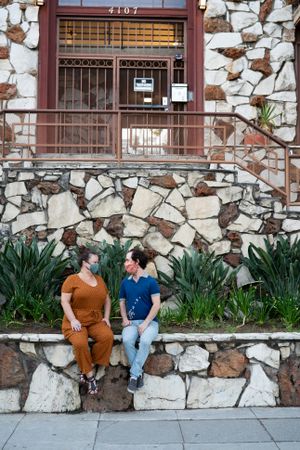 Happy friends talking outside wearing masks in front of apartment building