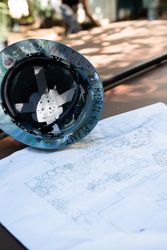 Hard hat with “born to plant” on the rim sitting outside with blue print