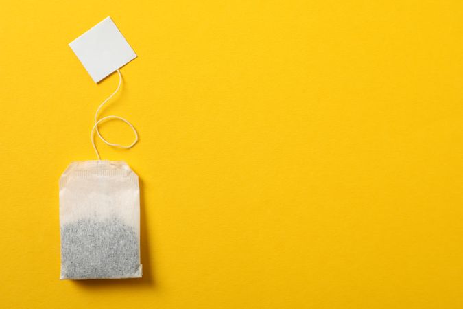 Tea bag with label on yellow background, space for text