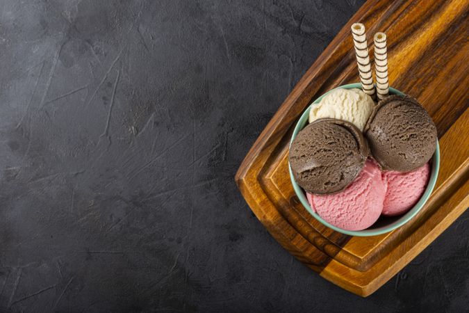 Bowl with Neapolitan ice cream on dark background.