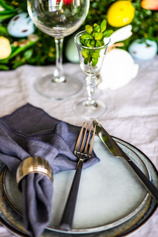 Spring table setting with plates on table with leafy centerpiece