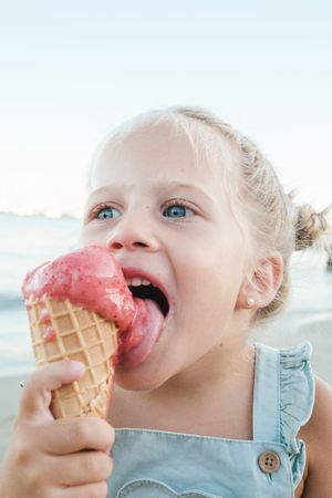 Girl licking ice cream in waffle cone in nature