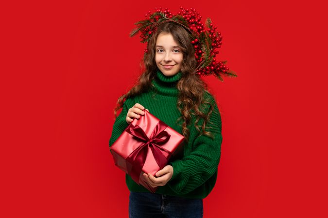 Young girl in green sweater holding wrapped red gift