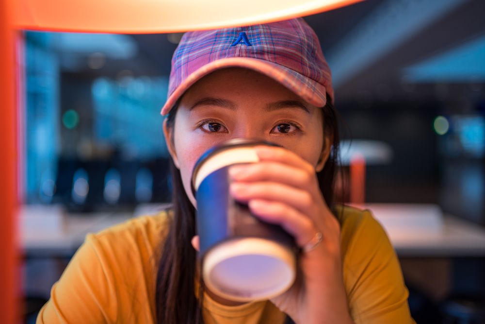 Asian woman drinking coffee at table under lighting lamp