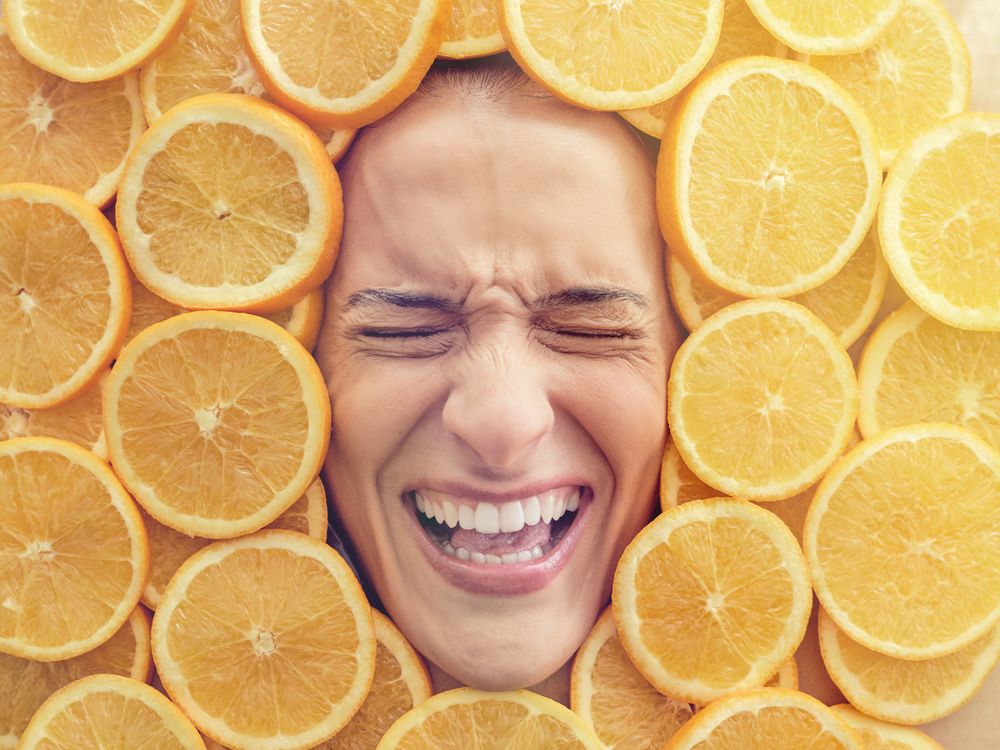 Discontent woman immersed in pile of cut oranges