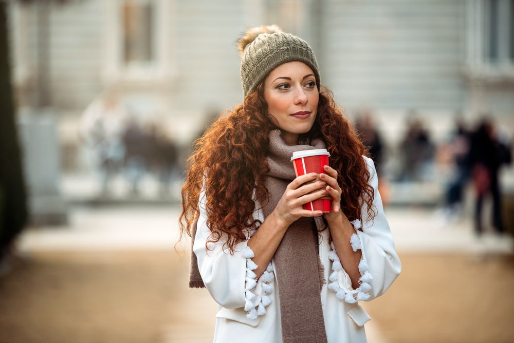 Woman drinking coffee wandering in the streets of Madrid on winter
