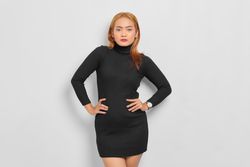 Asian woman looking at camera with hands on hips, red hair and turtle neck dress in studio