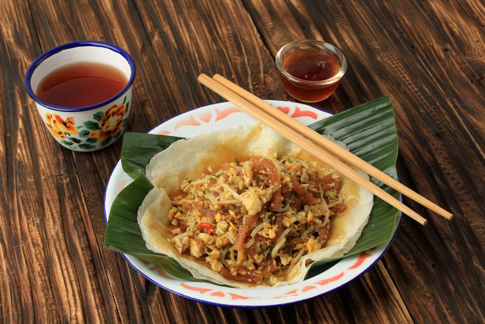 Lumpia dish served with chopsticks, dip and tea