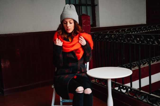 Pensive woman in warm wear sitting near steps in house