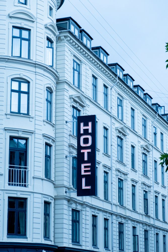 Lit hotel sign against light building