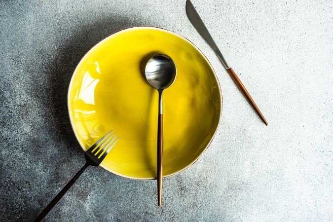 Minimalistic yellow table setting with plate and cutlery