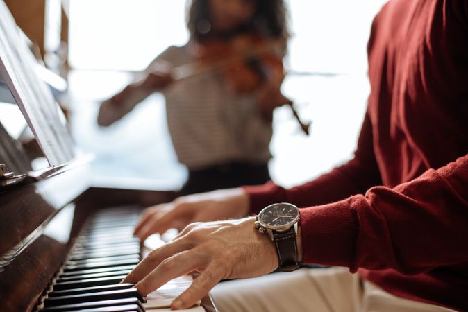 Man playing piano near woman playing violin in studio