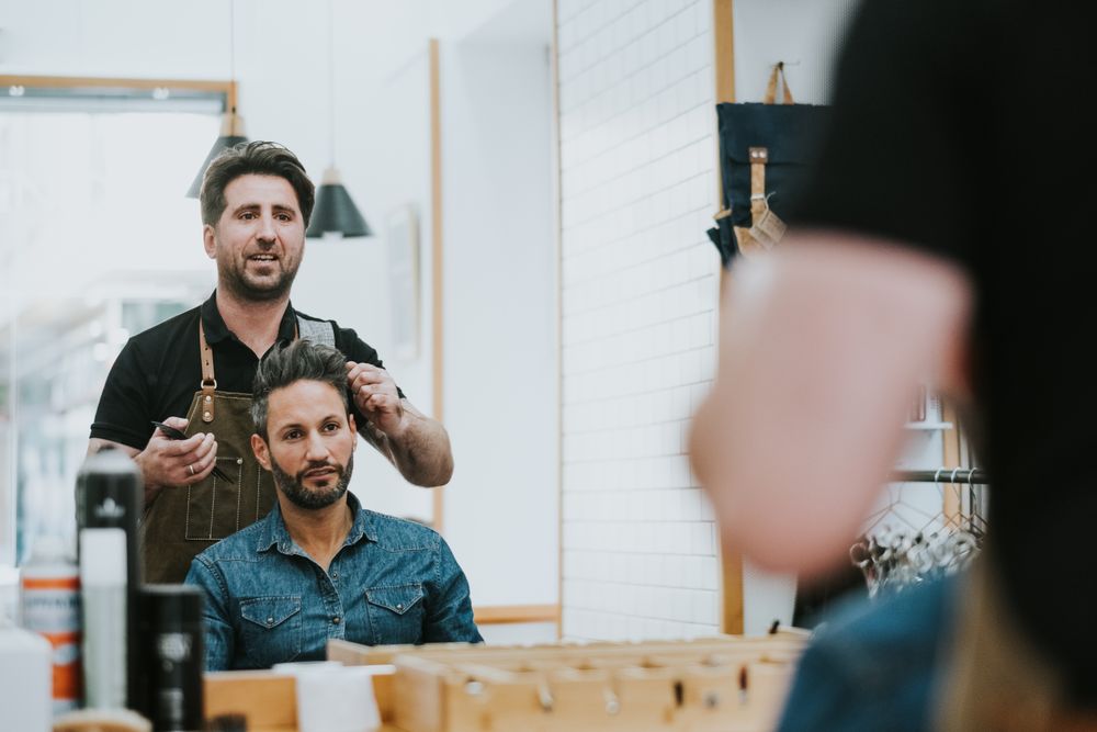 Barber combing hair to man in salon