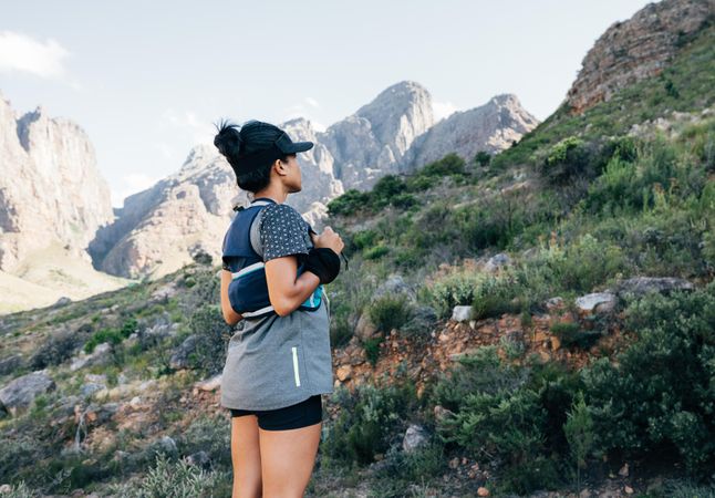 Healthy female stopped to enjoy the view while hiking through trail in a valley