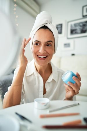 Happy woman applying face cream