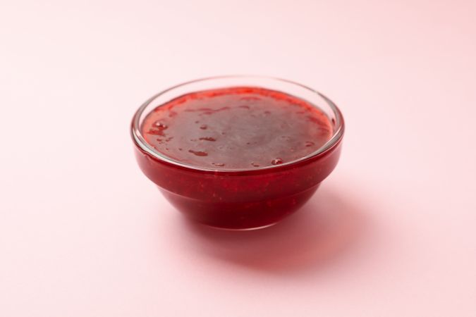 Delicious strawberry jam on pink background, close up