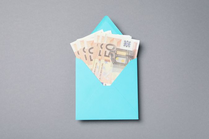 Money in a blue envelope on a gray background.