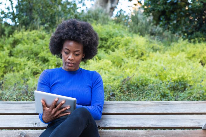 Serious Black woman browsing tablet in city