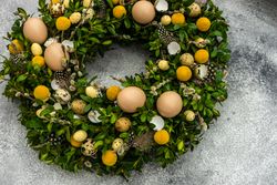 Top view Easter card concept with fresh wreath with decorative eggs and feathers