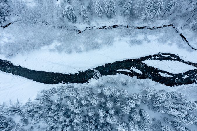 Drone image with snowy forest and river in the Bavarian Alps, Germany.