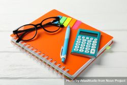 Orange notebook with glasses and stationary on table 5lJovb