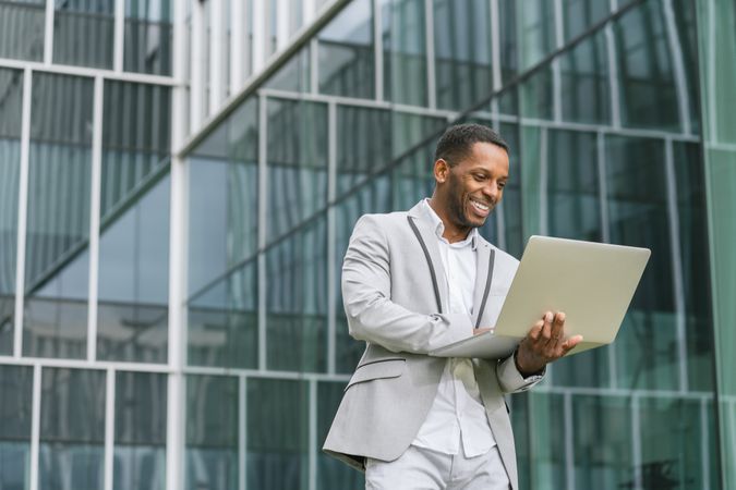 Self-sufficient Black man working in laptop in hands on street
