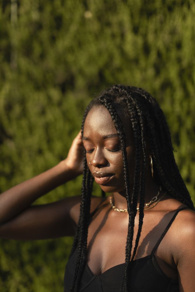 Portrait of a young Black female removing her hair from her face whit her eyes closed
