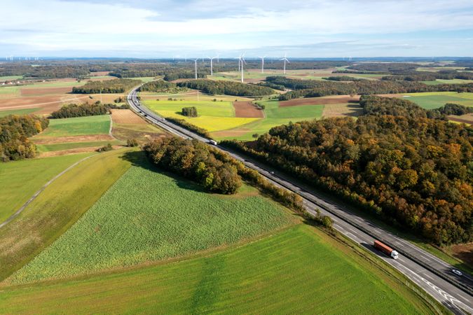 Aerial view with a two-lane highway and wind turbines in an autumn set