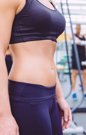 Torso of fit woman in busy gym