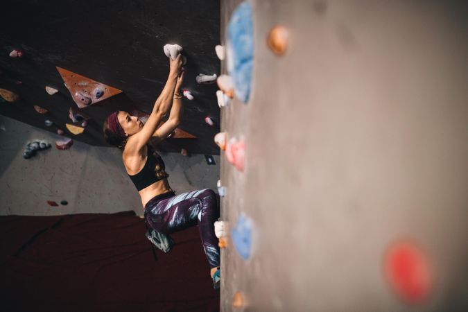 Skilled female rock climbing instructor practicing at indoor gym