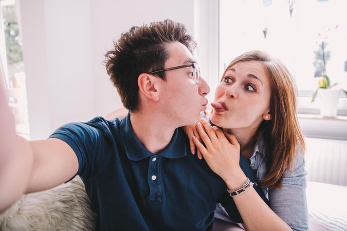 Young couple taking a selfie making silly faces at each other