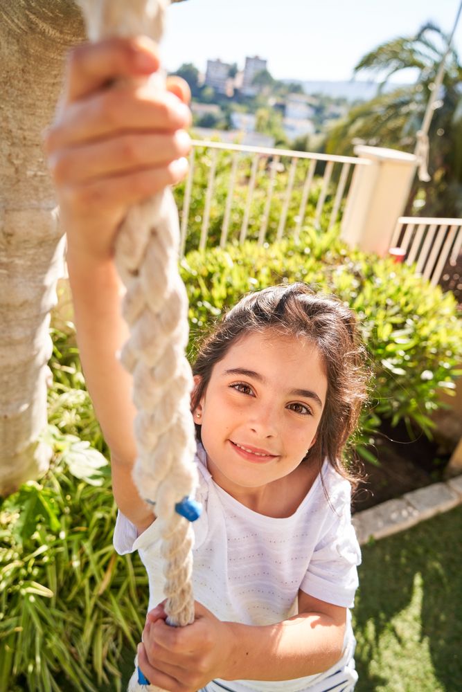 Smiling girl on rope swing in park