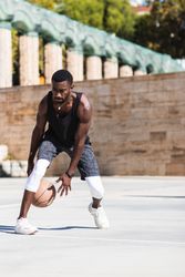 Black man playing basketball on sports ground