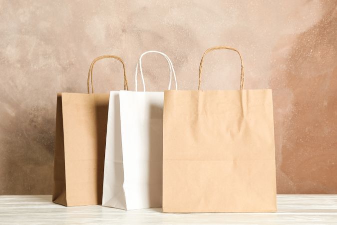 Paper bags on table against brown background, copy space