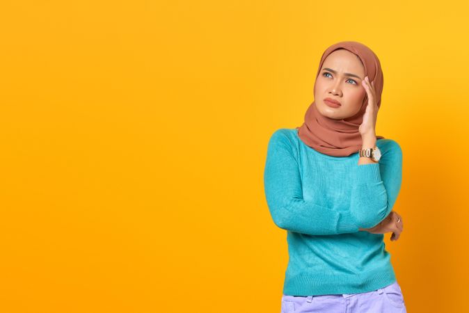 Muslim woman deep in thought with hand on her temple
