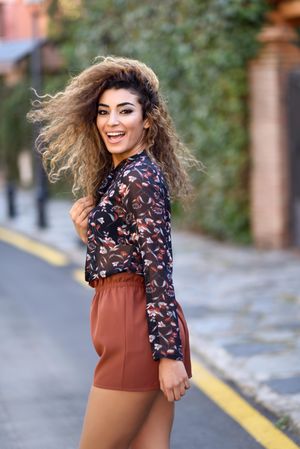 Laughing Arab woman looking back while wearing casual clothes in the street