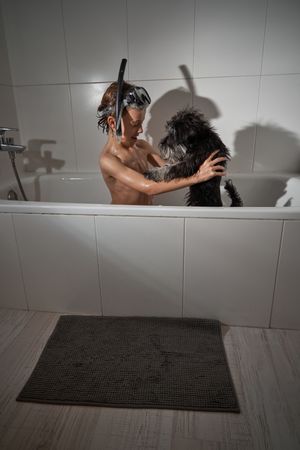 Boy playing with dog in bathtub