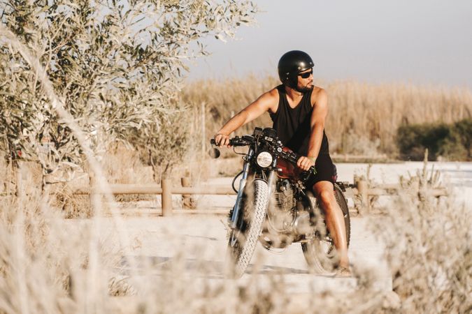 Serious male driving motorcycle in forest
